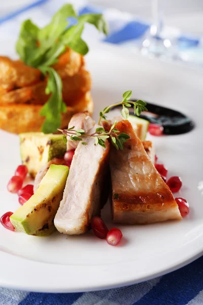 Grilled meat  with fried potato and marrow pieces and pomegranate seeds on plate, on wooden table background — Stock Photo, Image