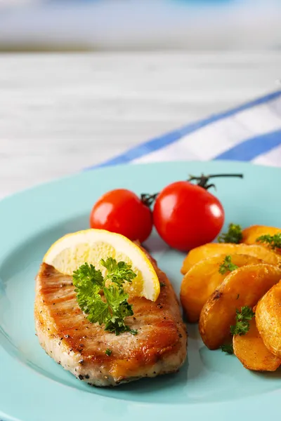 Bistecca alla griglia, verdure alla griglia e pezzi di patate fritte sul tavolo, su sfondo brillante — Foto Stock