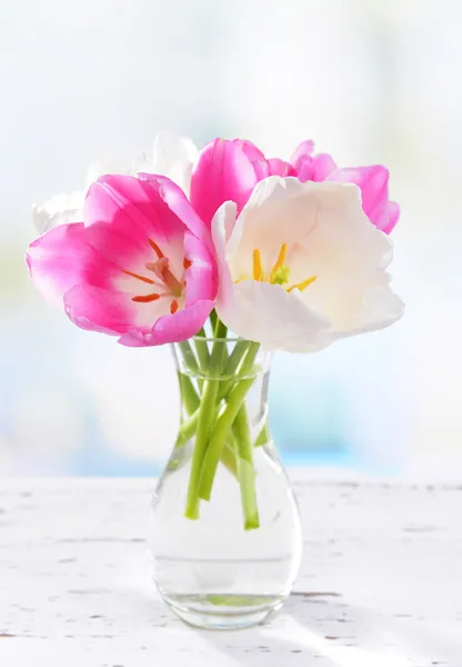 Piękne tulipany w wiaderku w wazonie na stole na jasnym tle — Zdjęcie stockowe