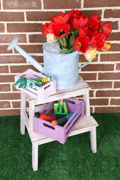 Состав разноцветных тюльпанов в банке для полива и оборудование для садоводства на ярком фоне — стоковое фото