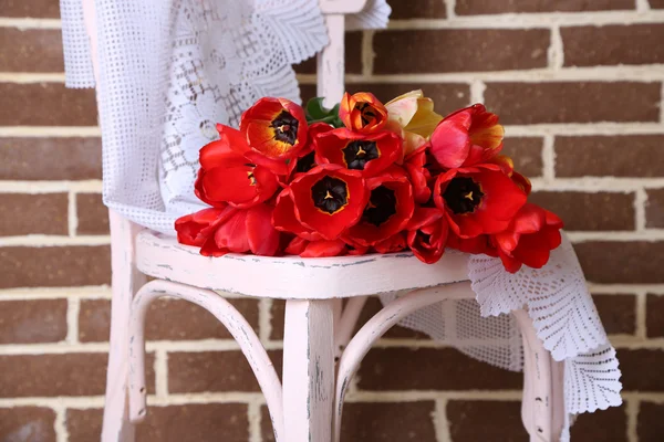 Bouquet of colorful tulips on chair, on home interior background — Stock Photo, Image