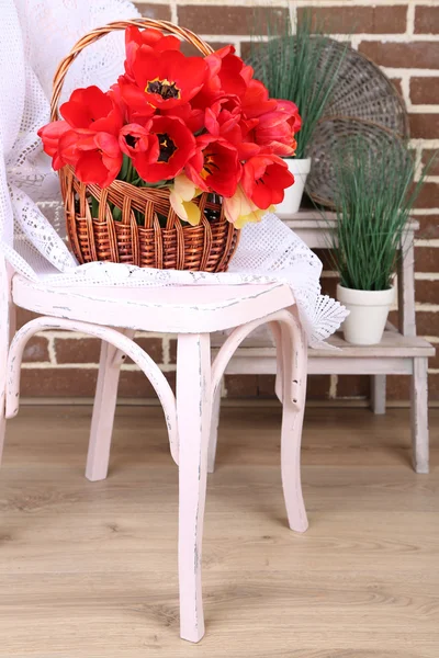 Buquê de tulipas coloridas em cesta de vime, na cadeira, no fundo interior da casa — Fotografia de Stock