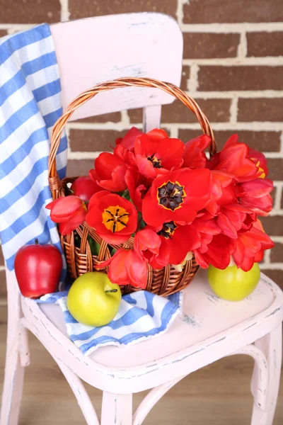 Bouquet of colorful tulips in wicker basket, on chair, on home interior background — Stock Photo, Image