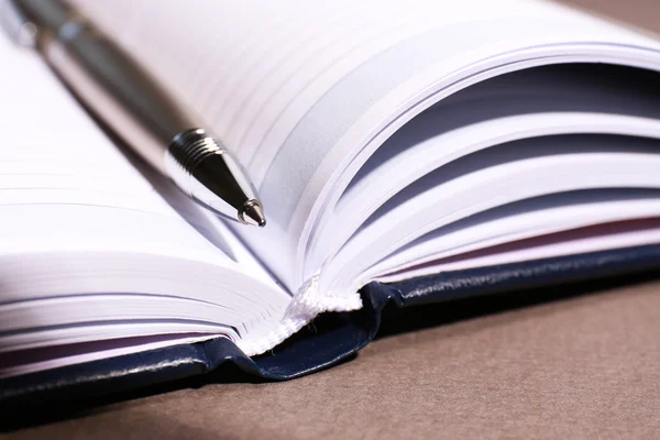 Pen on opened book on brown table, close up — Stock Photo, Image