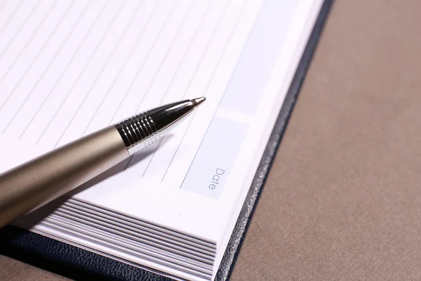 Pen on opened book on brown table, close up — Stock Photo, Image