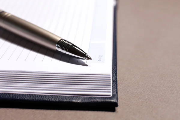 Pen on opened book on brown table, close up — Stock Photo, Image