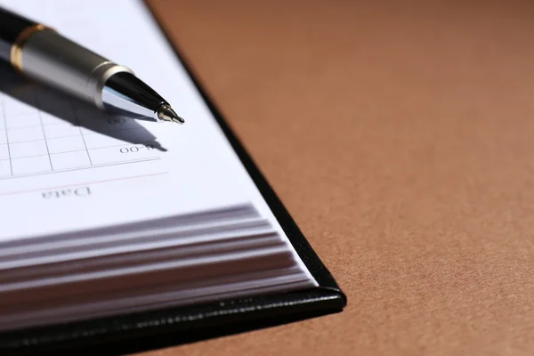 Caneta sobre livro aberto sobre mesa marrom — Fotografia de Stock