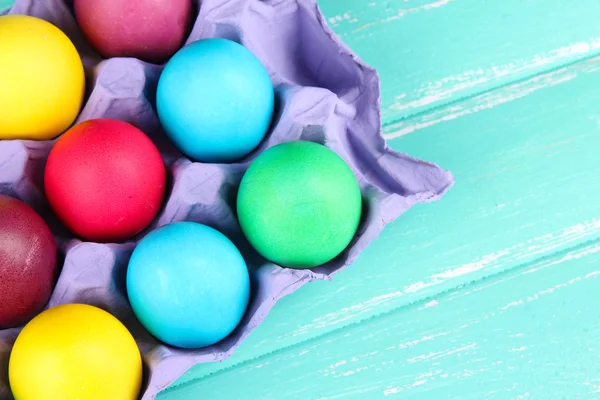 Coloridos huevos de Pascua en bandeja sobre fondo de madera — Foto de Stock