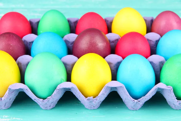 Barevné velikonoční vejce v zásobníku na dřevěné pozadí — Stock fotografie