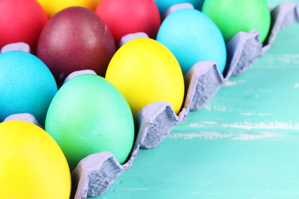Colorful Easter eggs in tray on wooden background — Stock Photo, Image