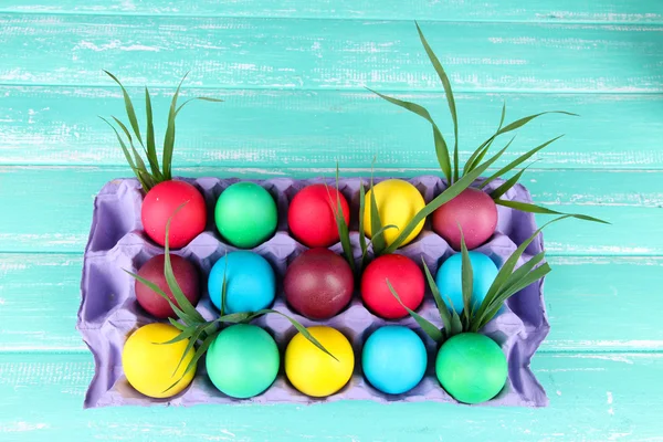 Huevos de Pascua coloridos con hierba en bandeja sobre fondo de madera — Foto de Stock