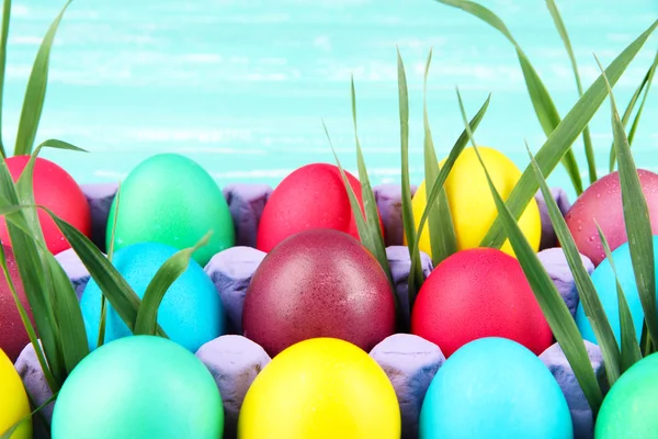 Huevos de Pascua coloridos con hierba en bandeja sobre fondo de madera —  Fotos de Stock