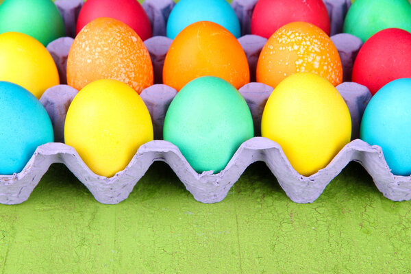 Colorful Easter eggs in tray on wooden background