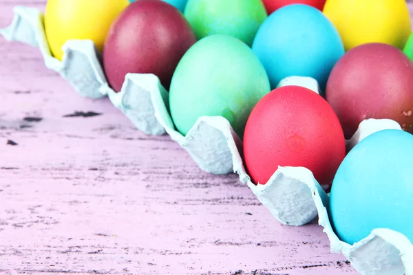 Tepsi ahşap arka plan üzerinde renkli Paskalya yumurtaları — Stok fotoğraf