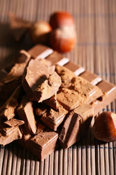 Chopped bar of chocolate on bamboo mat background — Stock Photo, Image