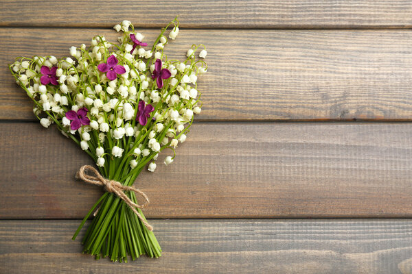 Beautiful lilac flowers and lilies of the valley, on wooden background