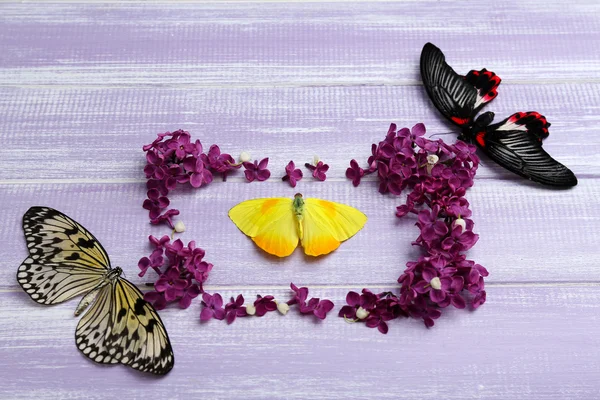 Beautiful lilac flowers and butterflies on wooden background — Stock Photo, Image