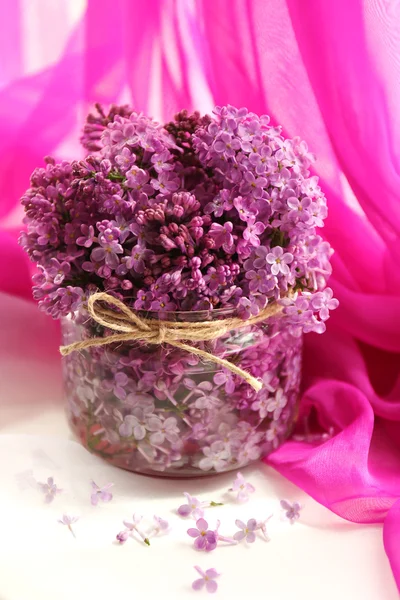 Beautiful lilac flowers in glass jar — Stock Photo, Image