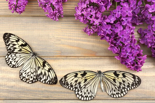 Mooie vlinders en lila bloemen, op houten achtergrond — Stockfoto