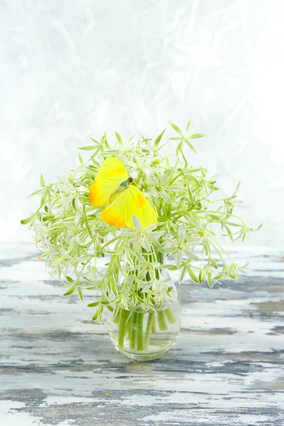 Beautiful butterfly sitting on spring flowers, on wooden table — Stock Photo, Image