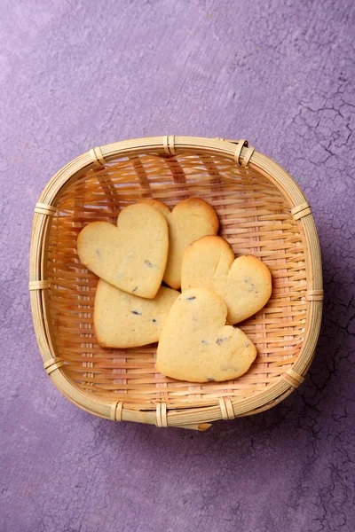 Cookies à la lavande dans un panier en osier, sur fond de bois couleur — Photo
