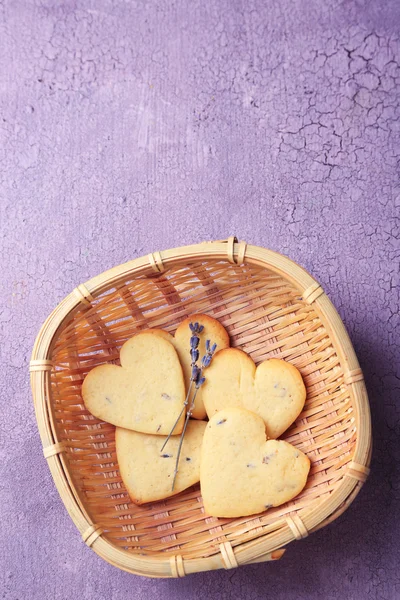 Лавандовое печенье в плетеной корзине, на фоне цвета дерева — стоковое фото