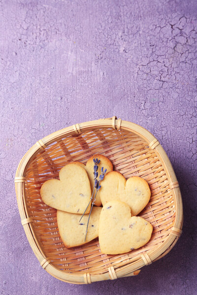 Lavender cookies in wicker basket, on color wooden background