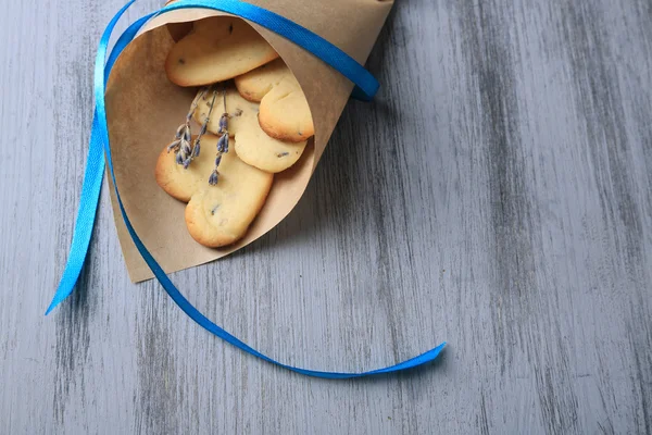 Lavender cookies in paper bag, on color wooden background — Stock Photo, Image