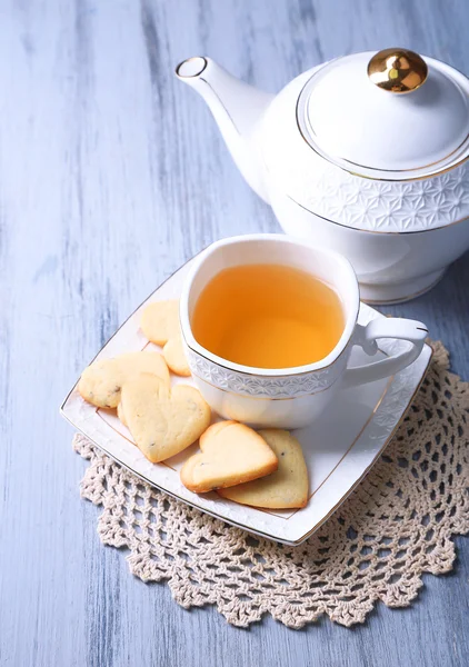 Lavender cookies and cup of tasty tea on color wooden background — Stock Photo, Image