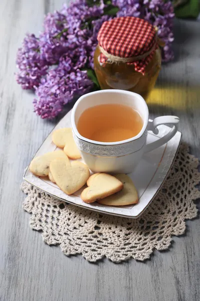 Lavendelkekse und eine Tasse leckeren Tee auf farbigem Holzhintergrund — Stockfoto