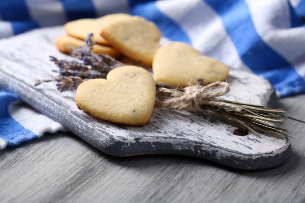 Cookies lavande sur planche à découper, sur fond de serviette de couleur — Photo