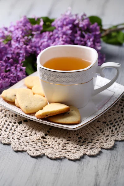 Lavender cookies and cup of tasty tea on color wooden background — Stock Photo, Image