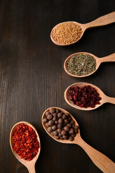 Different spices in spoons on wooden background — Stock Photo, Image