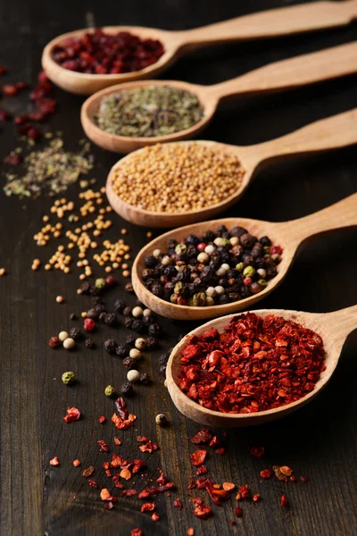 Different spices in spoons on wooden background — Stock Photo, Image