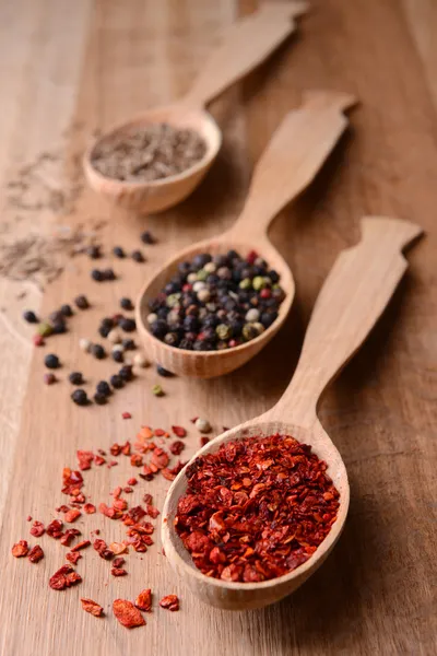 Ulike krydder i skjeer på trebakgrunn – stockfoto