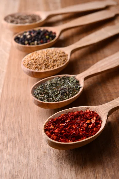 Different spices in spoons on wooden background — Stock Photo, Image