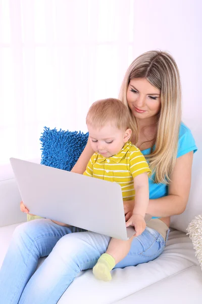 Mãe e filho com laptop no sofá em casa — Fotografia de Stock