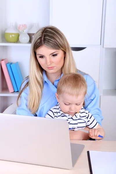Mulher bonita com bebê trabalhando em casa — Fotografia de Stock
