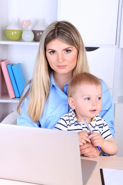 Mujer bonita con bebé trabajando en casa — Foto de Stock