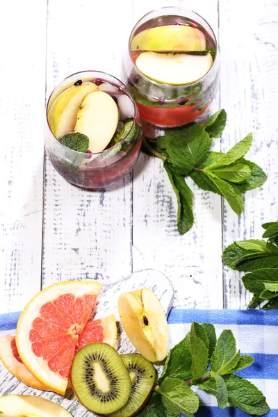 Cóctel sabroso con frutas frescas y hojas de menta sobre fondo de mesa de madera — Foto de Stock