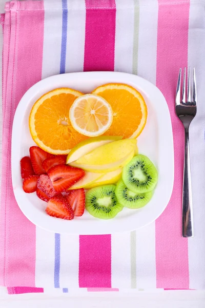 Various sliced fruits on plate on napkin close-up — Stock Photo, Image