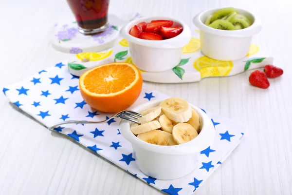 Various sliced fruits in bowls on table close-up — Stock Photo, Image