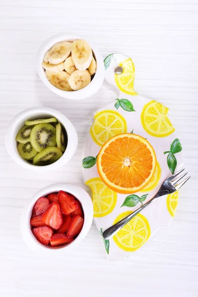 Various sliced fruits in bowls on table close-up — Stock Photo, Image