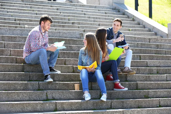 Estudiantes felices sentados en escaleras en el parque —  Fotos de Stock