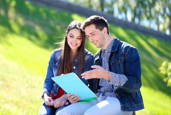 Felices estudiantes sentados en el parque — Stockfoto