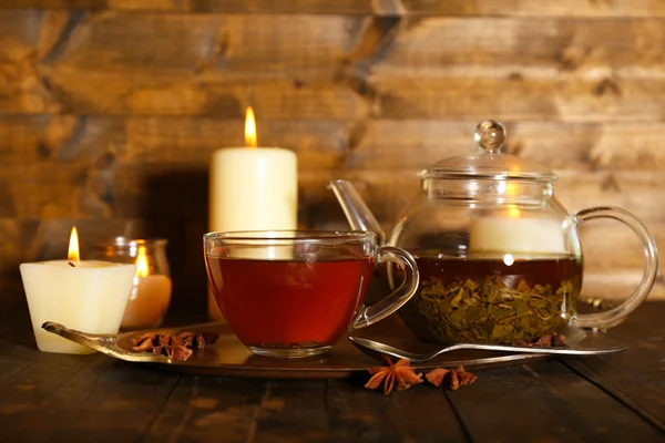 Composition avec thé en tasse et théière et bougies sur table, sur fond bois — Photo