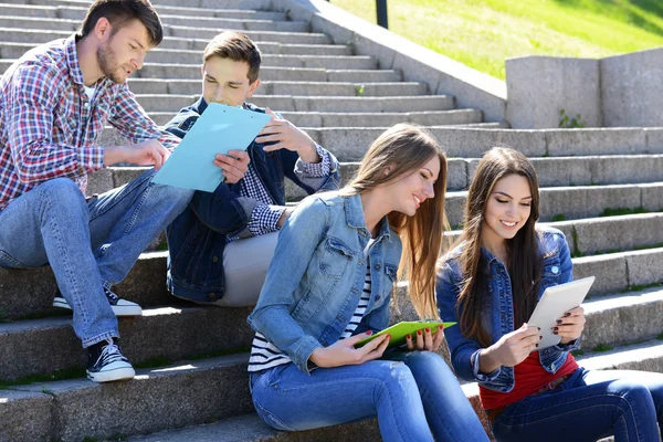 Glückliche Studenten sitzen auf Treppen im Park — Stockfoto