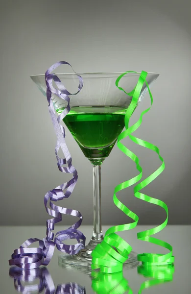 Glas Cocktail und Luftschlange nach der Party auf grauem Hintergrund — Stockfoto
