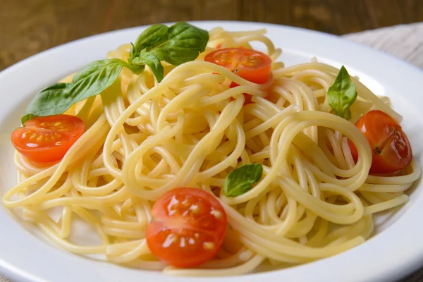 Heerlijke spaghetti met tomaten op plaat op tabel close-up — Stockfoto