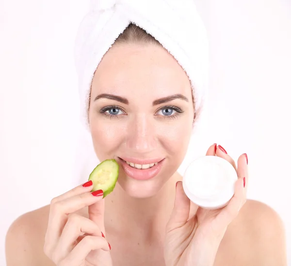 Beautiful young woman holding  fresh cucumber slices  and bowl with cream, isolated on white — Stock Photo, Image